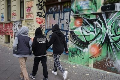 Rear view of friends walking by graffiti wall