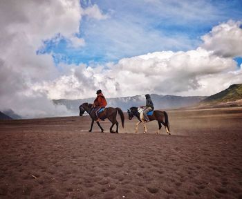 Full length of women riding horse on field against sky