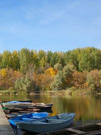 Boats moored by lake against sky during autumn