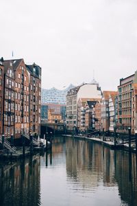 Buildings by river against sky in city