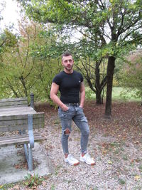 Portrait of young man standing against trees