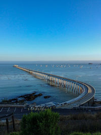 Scenic view of sea pier against clear blue sky