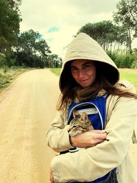 Portrait of woman embracing cat while standing on road