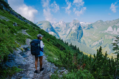 Rear view of man looking at mountains against sky