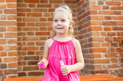 Portrait of cute girl standing against brick wall