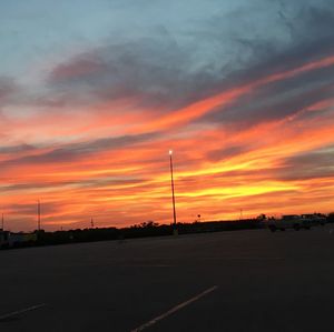 Scenic view of road against cloudy sky at sunset