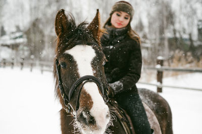 Beautiful woman riding horse on snow covered field