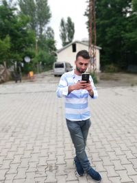 Young man using phone on footpath