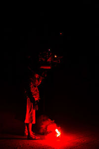 Man standing against illuminated red lights at night