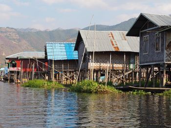 Houses by river and buildings against sky