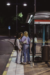 Rear view of people standing at railroad station