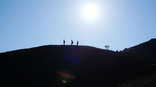 Low angle view of silhouette people on mountain against sky