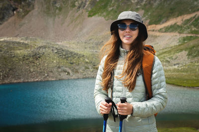 Female tourist enjoys the view of mountain peak rock and lake. idea of ecotourism. travel concept