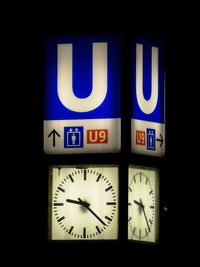 Close-up of illuminated clock over black background