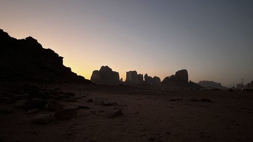 Rock formations on landscape against clear sky during sunset