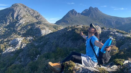 Woman sitting on rock against mountains