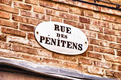 Close-up of information sign on brick wall