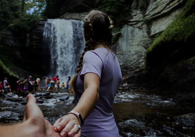 Rear view of woman against rock in water