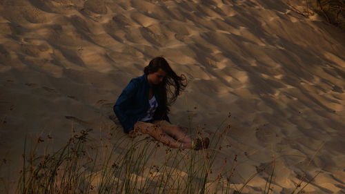 Woman sitting on sandy beach