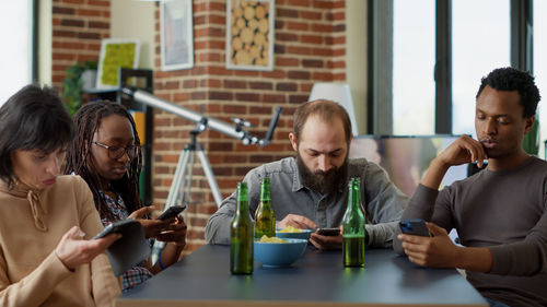 Friends using mobile phone while sitting on table