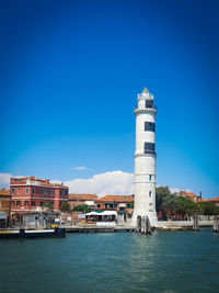 Buildings by sea against clear blue sky, lightning tower, burano