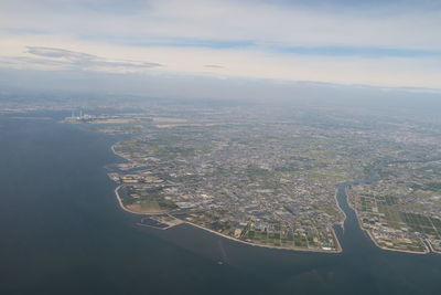 Aerial view of city by sea against sky