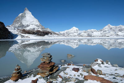 Scenic view of snowcapped mountain matterhorn reflection in lake against blue sky