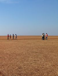 People standing on beach against clear sky