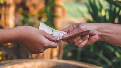 Cropped image of people holding paper against blurred background