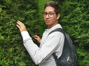 Portrait of young man standing against plants