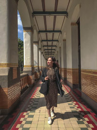 Full length of woman standing against building