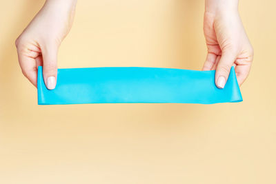 Close-up of hands holding blue over white background