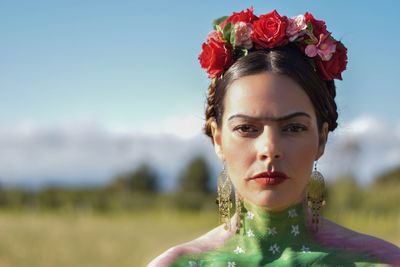 Portrait of woman with pink flower against sky