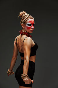 Low angle view of young woman standing against black background