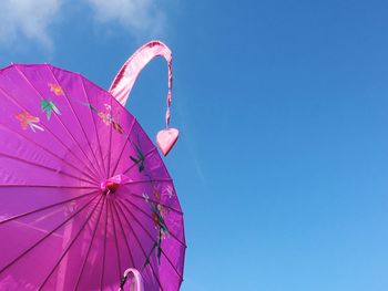 Low angle view of pink parasol against blue sky