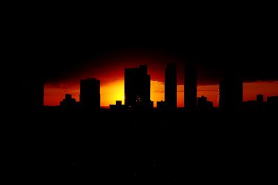 Silhouette of buildings against sky at sunset