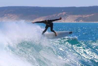 Man with arms outstretched surfing on sea