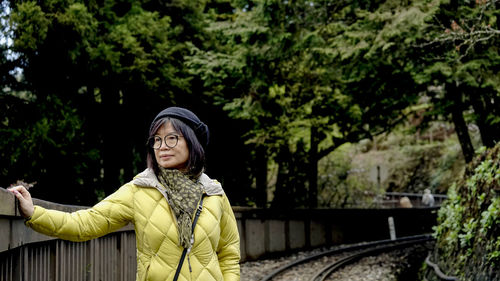 Portrait of woman standing by trees