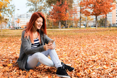 Young woman using phone while sitting on street