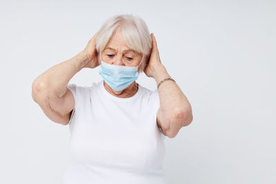 Portrait of young woman wearing mask against white background