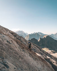 Young man hiking on mountain against sky during sunny day