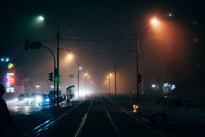 Foggy city street with tram ways during autumn at night