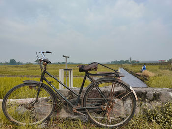 Bicycle parked on field against sky