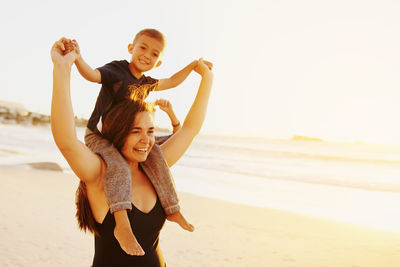 Portrait of happy friends enjoying at beach against sky