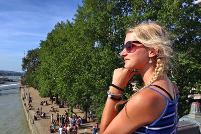 Beautiful woman wearing sunglasses looking away standing against trees