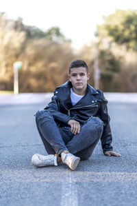 Portrait of young man sitting on road