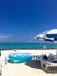 Deck chairs on beach against blue sky