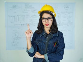 Portrait of young woman standing against wall