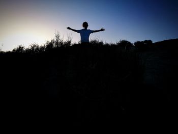 Silhouette man standing on field against sky during sunset