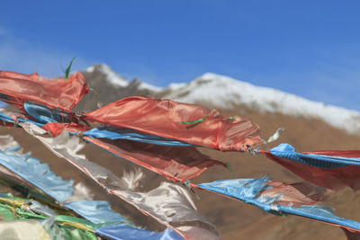 Close-up of prayer flags waving on mountain against clear blue sky